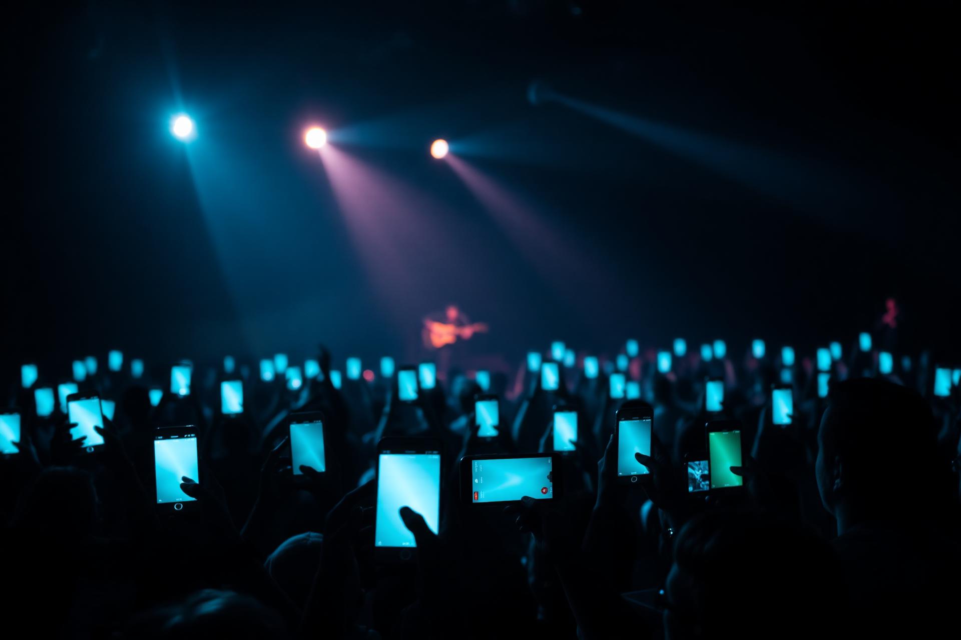 Concert audience holding glowing phones in sync with the stage